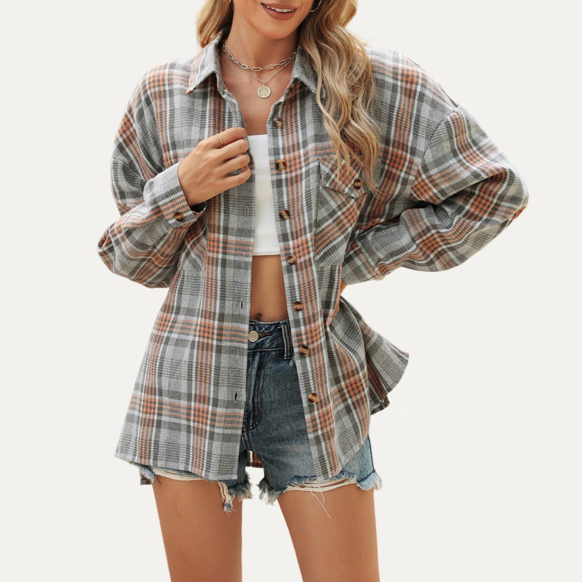 Woman wearing a plaid shirt over a white top and denim shorts on a white background