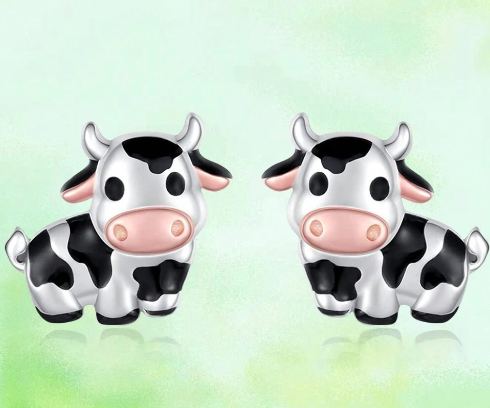Pair of cow-shaped earrings on a light green background